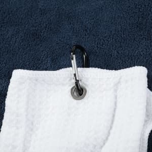 A white golf towel featuring a zippered pocket and a metal carabiner for attachment, set against a navy background.
