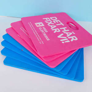 A stack of seat cushions in pink and blue colours, featuring a handle for easy carrying.