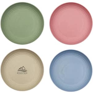 A set of four unbreakable plates in green, pink, blue, and beige, featuring a logo on one plate.