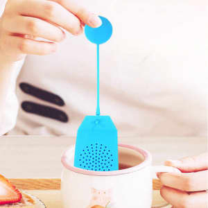 A blue reusable silicone tea bag with a long rope is being used in a cup. It has a circular top and perforated design.