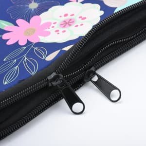 A zippered neoprene laptop sleeve features a floral design in pink and white on a navy background, with dual black zippers.