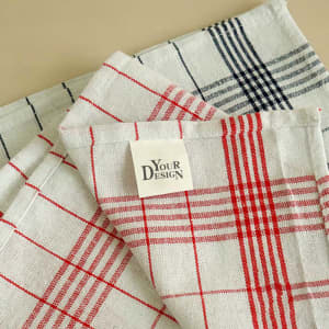 Classic plaid check tea towels in red, white, and navy blue, featuring a label and a woven texture.