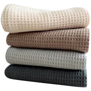 Four stacks of cotton waffle absorbent kitchen cloths in beige, brown, grey, and charcoal colours. The image includes a logo.