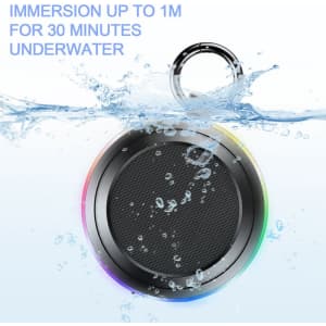 A portable wireless shower speaker with a round black design and a multi-coloured light ring, partially submerged in water.