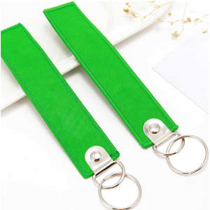A vibrant green custom embroidered airplane key tag featuring metal key rings for attachment.