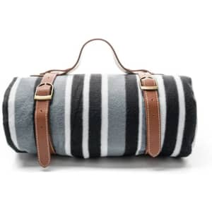 A rolled fleece picnic blanket in grey and black stripes, secured with two brown leather straps.