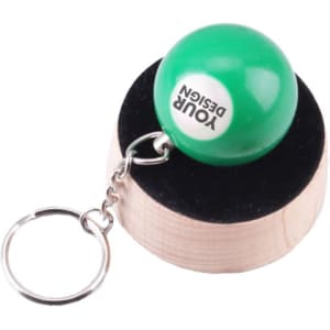 A green billiard ball keychain attached to a silver keyring, displayed on a wooden stand.