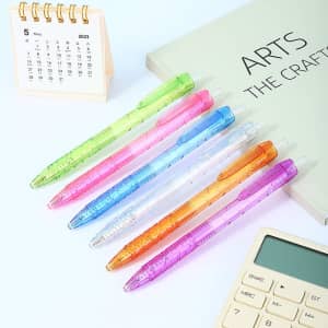 A collection of RPET ballpoint pens in pink, green, blue, clear, and purple, displayed alongside a calendar and calculator.