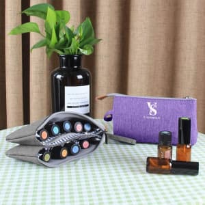 A purple toiletry bag with essential oil bottles, displayed alongside a black vase and a green plant on a checkered tablecloth.