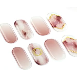 A set of ten gel nail stickers in shades of pink and marble, with a gold accent design.