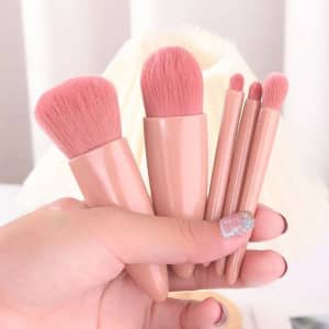 A set of five pink makeup brushes held in a hand, featuring soft bristles and sleek handles.
