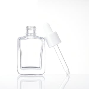 A flat square glass dropper bottle in clear glass with a white dropper top. The bottle has a minimalist design.