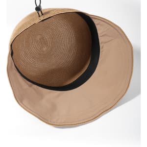 A tan straw baseball cap with a wide brim and a black inner lining, featuring a logo on the exterior.