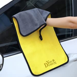 A thickened coral velvet car cleaning cloth in yellow and grey, draped over a car door. It features a loop for hanging.