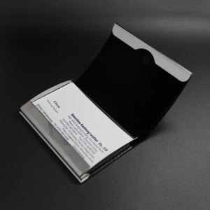 A stainless steel card holder with a sleek black interior, featuring a logo on the exterior.