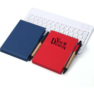 Two standing notepads, one navy blue and one red, with a pen, placed beside a keyboard. Each has a branding logo.