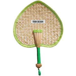 A heart-shaped woven fan in natural tones with a green trim and handle. It features a designated area for custom designs.