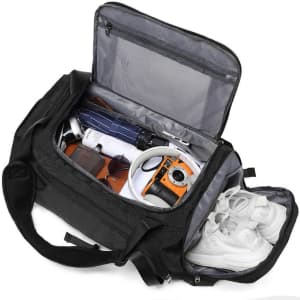 A large black travel duffel bag is open, revealing shoes, a camera, sunglasses, and a drink bottle inside.