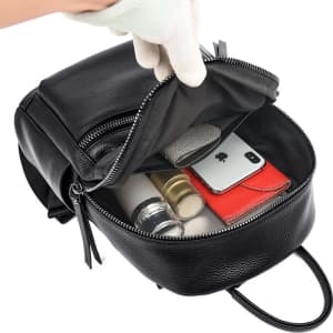 A black genuine leather backpack with an open zipper, revealing compartments for a phone, cosmetics, and cards.