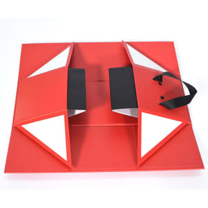 A red collapsible wine box with black handles and triangular flaps, featuring a logo.