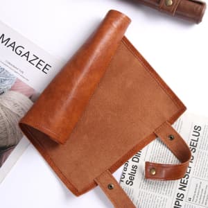 A foldable pu leather dice bag in a rich brown colour with a smooth finish and snap fasteners.