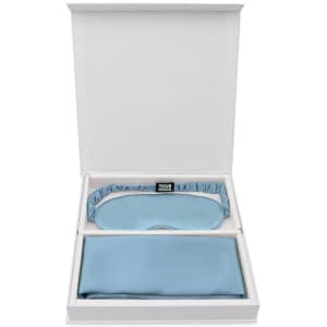 A boxed set featuring a light blue silk eye mask and a matching silk pillowcase. The box has a logo.