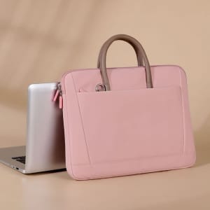 A pink laptop briefcase shoulder bag next to a silver laptop, featuring a sleek design and dual handles.