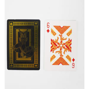 Two playing cards displayed: one black with gold design and the other in white and red featuring intricate patterns and numbers.