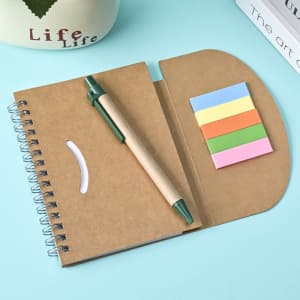 A brown spiral notebook with a green pen and coloured sticky notes in pastel hues on a light blue background.