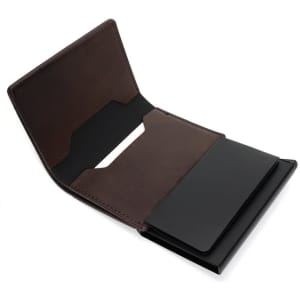 A brown leather business card holder with a black RFID blocking section, featuring a simple logo design.