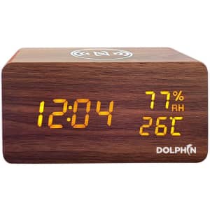 A wooden digital alarm clock with an orange display showing time, humidity, and temperature. It features a logo.