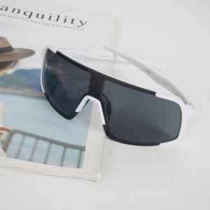 Polarized UV protection sunglasses with a black and white frame, resting on a magazine.
