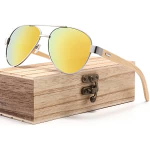 Classic bamboo temples sunglasses with a reflective gold lens, resting on a wooden box. The design is stylish and modern.