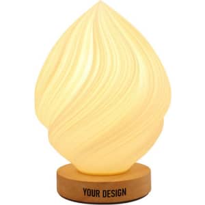 A personalized bedside table lamp in a soft yellow hue with a swirled design on a wooden base. It features branding.
