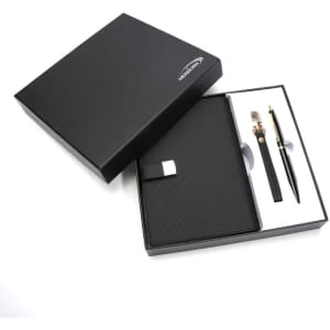 A black gift box containing a black notebook and a gold-accented pen, presented elegantly.