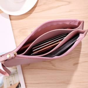 A pink double-layer wallet showcasing multiple card slots and a zippered closure, displayed on a wooden surface.