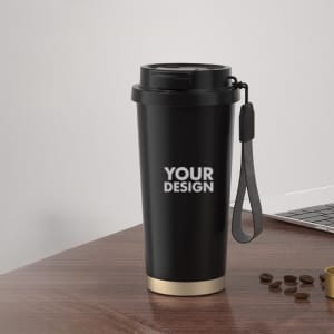 A travel mug in black stainless steel with a gold base and a handle, featuring a logo.