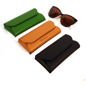 A collection of three PVC leather glasses cases in green, tan, and black, alongside a pair of sunglasses.