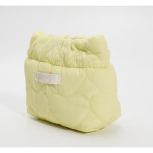 A compact cosmetic bag in soft yellow with a quilted heart pattern, featuring a gathered top and a decorative strap.