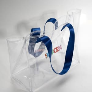 A large transparent tote bag with blue straps and a logo, showcasing a clear design suitable for various items.