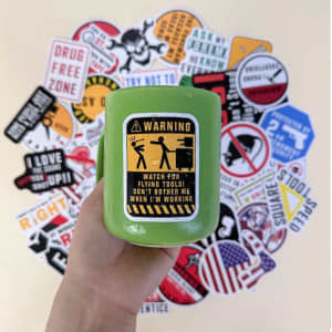 A green drink bottle held in hand, surrounded by a variety of stickers with different designs and colours.