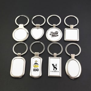A collection of silver metal blank keychains in various shapes, including circular, heart, rectangular, and oval designs.