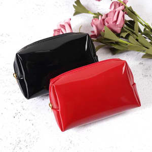 A portable travel makeup bag set featuring a black and a red glossy design, beside some pink flowers.