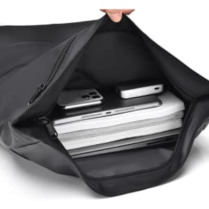 A black expandable daypack interior featuring a laptop, documents, and mobile devices in an organised layout.