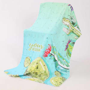A soft, quick-drying beach towel in mint green with a cactus design and vibrant floral accents, featuring a logo.