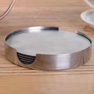 A set of stainless steel round coasters in a holder on a wooden surface. The coasters have a sleek, shiny finish.