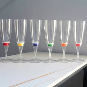 Six transparent champagne glasses with coloured LED bands in yellow, blue, green, orange, and red.