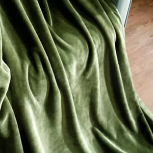 A soft, green flannel lap blanket draped elegantly, showcasing its smooth texture and plush appearance.