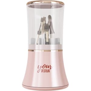 A rotating makeup brush holder in a sleek pink and gold design, featuring various makeup brushes inside.