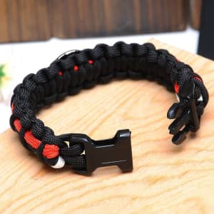 A black and red woven paracord bracelet with a black clasp, resting on a wooden surface.
